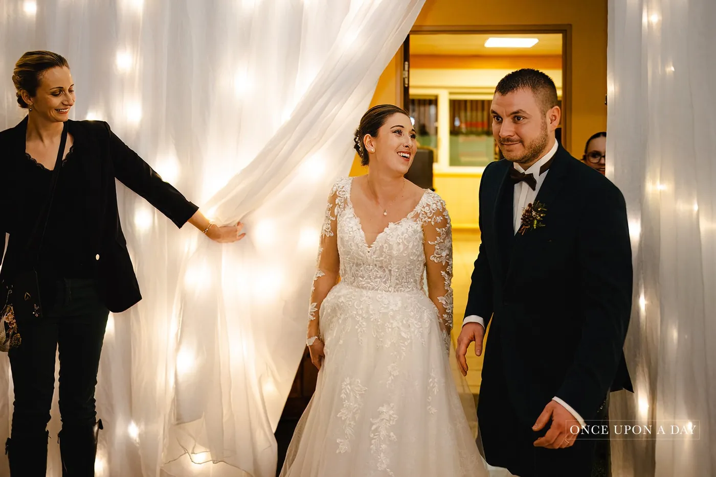 Amandine opening the curtain for the couple's entrance